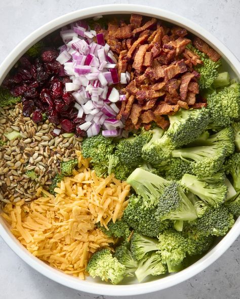 overhead shot of all the ingredients of the broccoli salad organized in a circle around a large white bowl. Dinners Crockpot, Delicious Magazine Recipes, Healthy Broccoli Salad, Trending Food, Broccoli Salad Bacon, Resep Salad, Broccoli Salad Recipe, Magazine Recipes, Yogurt Dressing