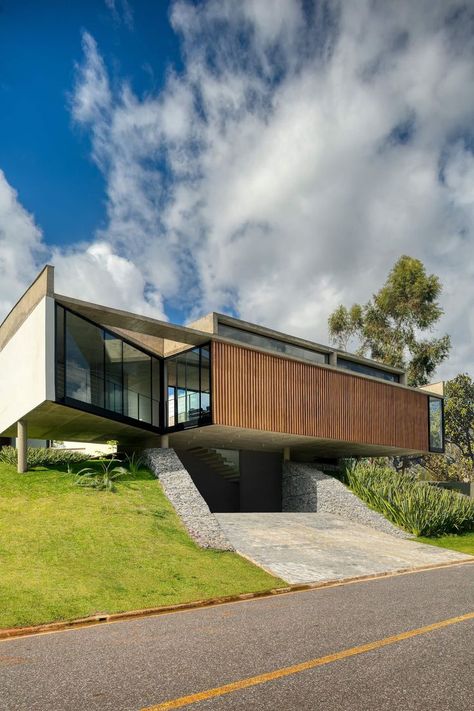 The 7 Patios House is located in a private condominium in Nova Lima, Brazil. The site has a slight slope, no vegetation, and is located close to the condominium limits. Right outside this limit is a highway. The noise from cars can be heard from inside the land. Right in front of the land, across the highway, a factory can be seen, so the best views are looking diagonally. From both sides, it is possible to see the forest and the mountains, typical of Minas Gerais. #architecture #architect Nova Lima, Slope House, A Modern House, Entry Ideas, Garage Entry, One Story Homes, A Hill, Story House, Residential Architecture