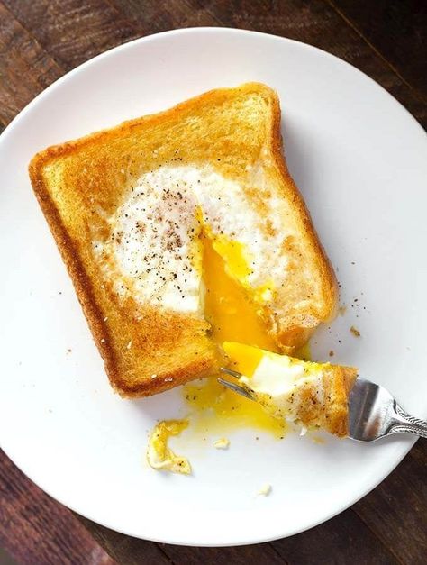 Egg in a Hole is a delicious piece of toast that has an egg soft cooked in the center, which has been cut out. This popular breakfast has many names, like Toad in a Hole, egg in a frame, egg in the basket, but this egg in toast recipe is delicious no matter what you call it! simplyhappyfoodie.com Dropped Eggs On Toast, Eggs In Bread Hole Recipes, Egg In A Hole Skillet, Bread With Egg In Middle, Eggs In A Hole, Egg Toast Breakfast, Simply Happy Foodie, Egg In A Hole, Over Easy Eggs