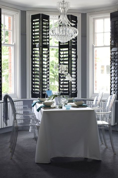 Mix up your monochrome scheme by opting for black gloss shutters over white. When combined with ghost dining chairs and a chic chandelier, the look is oh so glamorous.   Shutters from [link url="http://www.thecaliforniacompany.co.uk"]The California Company[/link]  [link url="http://www.houseandgarden.co.uk/homes/furnishings/lighting"]LIGHTING IDEAS WE LOVE[/link] Shutters Indoor, Bay Window Shutters, Indoor Shutters, Best Interior Design Websites, Interior Window Shutters, Black Shutters, Modern Blinds, Living Room Blinds, Interior Shutters