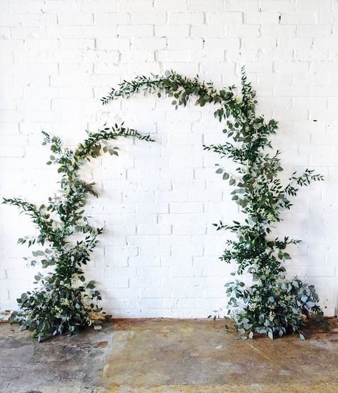 Free form wall installation of eucalytpus and ruscus greenery, with small accents of white waxflower. For wedding ceremony backdrop or other photo op at your event. at Norfolk Hall in Charlotte, NC. Greenery On Brick Wall Wedding, Greenery Garland Backdrop, Foliage Photo Backdrop, White Wall Wedding Backdrop, Wedding Flowers Pillars, Wedding Photo Wall Backdrop, Salon Photo Backdrop Wall, Greenery Backdrop Wedding, Greenery Wall Wedding