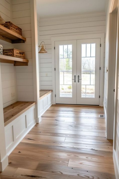 Bright entryway with wooden flooring, white shiplap walls, a built-in bench on the left, and double doors with glass panes letting in natural light. Colorado Modern Farmhouse, White Farmhouse Interior Design, Rustic Flooring Ideas Farmhouse Style, Mudroom With Bathroom, Backdoor Mudroom, White Farmhouse Interior, House Design Farmhouse, Farm House Mud Room, Mudroom Flooring Ideas