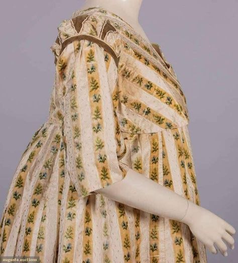 A round gown. This example is from 1798 and it was sold through Augusta Auctions. The silk fabric is striped. One stripe is a gold colored velvet that has been printed in the ikat style with flowers and foliage. That stripe alternates with white on white brocade stripes with an undulant ribbon pattern. Regency Sleeves, Regency Fabric, 1790s Fashion, 1800's Dress, Augusta Auctions, Historical Clothes, Regency Gown, Ribbon Pattern, New Century