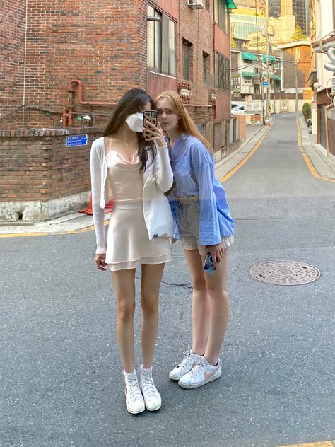 asian girl wearing pink silky slip dress, cardigan, and converse, european girl wearing paperbag shorts, blue buttondown shirt, and sneakers or trainers. aesthetic italian girl soft girl summer #fashion #y2k #italiansummer #europeansummer #thatgirl #itgirl #softgirl #cleangirl #aesthetic #aestheticallypleasing #bestfriends #friendsaesthetic #asiangirl #ulzzangoutfit #outfit #outfitinspo #slipdress Outfit With Paperbag Shorts, Slip Dress And Converse, Asian Outfits Summer, Trainers Aesthetic, Slip Dress Cardigan, European Girl, Dress With Converse, Ulzzang Outfit, Dress And Sneakers Outfit