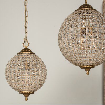 Bring brilliant style to your dining room, bedroom, or entryway with this glam single-light pendant. We love hanging this piece on its own or in multiples for a more dramatic look. It’s made of metal in a gold-tone and features an adjustable chain and an ornate header with a matching bottom finial. The globe shade features a cage design, which is covered in rows of clear crystals, which glitter in the light. This pendant requires one maximum 40W standard bulb (not included). It requires hardwiri 3 Light Hanging Pendant, Crystal Globe Pendant Light, Black And Gold Kitchen Chandelier, Victorian Kitchen Light Fixtures, Crystal Pendant Lighting Kitchen, Victorian Pendant Light, Modern Victorian Light Fixtures, Vintage Chandelier Living Room, Crystal Globe Chandelier