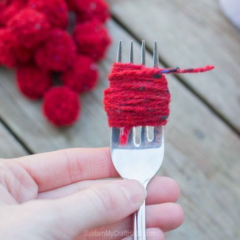 Red yarn would around a fork to create a DIY pom pom garland #christmas-crafts #decor #driftwood-crafts #garland #mantel #mantle #pompoms #scrap-yarn #yarn #yarn-projects#christmas-crafts #knitting-and-crochet-patterns #valentines-day-drafts #sustainmycrafthabit Christmas Garland Diy Yarn, Yarn Decorations Christmas, Diy Christmas Gnome Garland Yarn, Pompom Garland Christmas Tree, Diy Wool Christmas Decor, Easy Yarn Christmas Ornaments, Diy Christmas Pom Pom Garland, Christmas Yarn Garland Diy, Yarn Ball Garland