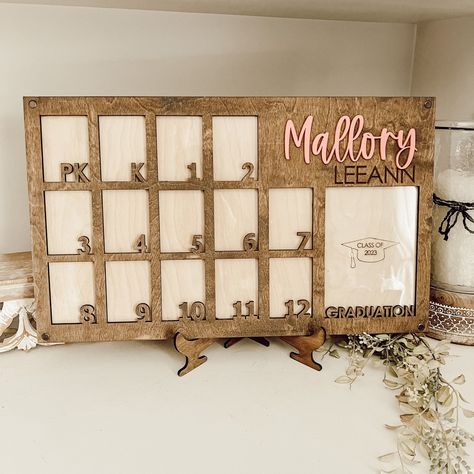 Watch them grow! Displaying their school photos as they grow will certainly be a joy! Free shipping in the continental U.S Overall dimensions 12" x 20" and the stand is included (stained to match the top board) There are also notches cut in the back to allow for hanging on the wall. Each box is perfect for a  2.5" x 3.5" wallet size photo. The graduation photo hold a 5" x 7" picture. The first name is printed in acrylic and the middle name engraved onto the board The top board is cut out of 1/4" School Pictures Display, School Years Picture Frame, School Picture Frames, Graduation Picture Frames, Graduation Photo Frame, Photo Frame Decoration, Graduation Frame, Photo Stand, Grade 12