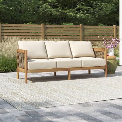 This patio sofa gives you a spot to relax on your porch or deck. It has a streamlined UV- and water-resistant solid acacia wood frame that rests on slightly tapered legs and features curved back corners for a graceful look. We love how the brown finish brings out the wood's natural grain for a coastal farmhouse feel. Breathable wicker rattan side accents and an open back complete the design. Beige-toned polyester cushions provide just the right amount of support as you enjoy casual coffee chats Outdoor Patio Sofa, Sofa With Cushions, Patio Daybed, Patio Couch, Outdoor Couch, Aluminum Patio, Sunbrella Cushions, Teak Outdoor, Patio Sofa