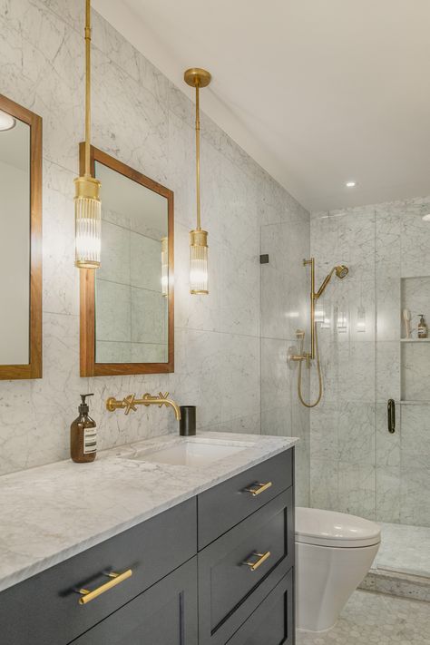 The master bathroom features a simple palette of walnut, brushed brass, marble, and dark gray cabinets. #masterbathroom #interiordesign #remodelideas #boardandvellum Grey Marble Bathroom, Brass Bathroom Fixtures, Grey Bathroom Cabinets, Dark Gray Bathroom, Condo Bathroom, Grey Bathroom Vanity, Modern Condo, Brass Bathroom, Downtown Seattle