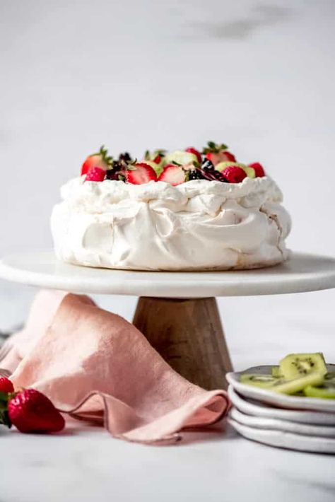 An Australian & New Zealand classic, Pavlova is a heavenly dessert confection that is light as a cloud with a crunchy meringue outside and soft, marshmallow-like interior. Topped with sweetened whipped cream and piled with fresh fruit, this dessert is always a crowd-pleaser and the perfect finish for any meal! #pavlova #meringue #classic #recipe #homemade #fromscratch #easy #authentic #australian #newzealand #dessert What Is Pavlova, Fruit Tart Glaze, Classic Pavlova Recipe, Pavlova Cake, Pavlova Recipe, Sweetened Whipped Cream, Fruit Compote, Fancy Desserts, Fruit Tart