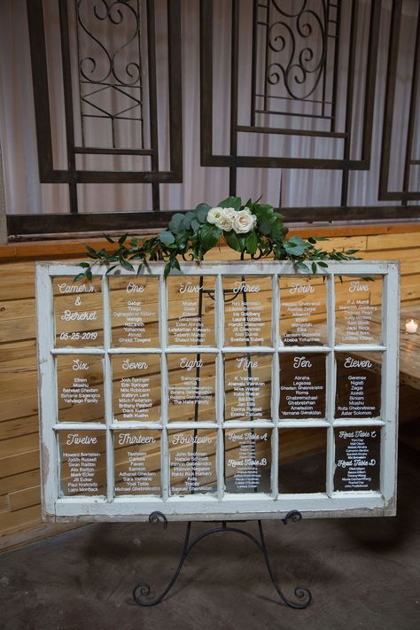 This bride chose to use an old rustic window to transform into a beautiful piece of wedding decor. Each window pane has a different table number for guests to find their seat during the reception.   Photo: Eva Rieb Photography Window Wedding Table Seating, Old Window Table Seating Chart, Rustic Wedding Window Decor, Old Window Wedding Seating Chart, Seating Chart Window Pane, Table Number Chart Wedding, Window Table Seating Chart, Old Windows Wedding Decor, Wedding Seating Chart Window