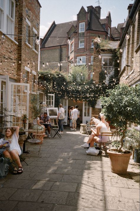 A bright summer day on a small street off Columbia Road Market in East London. The street has cafes with outdoor seating, and strings of fairy lights hanging between the buildings. Lucy Moon, Professional Overthinker, Columbia Road Flower Market, Columbia Road, London Lifestyle, The Good Witch, Travel Reading, Rustic Theme, London Life