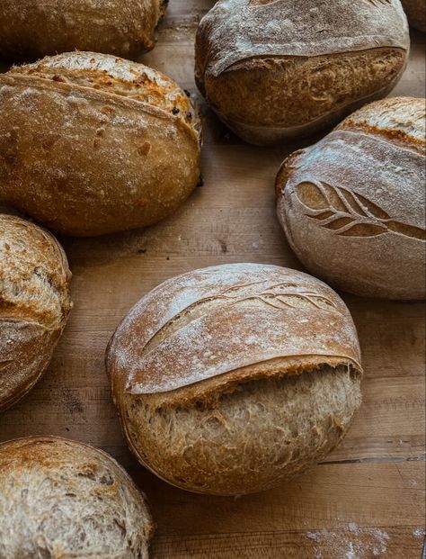 Multiple loaves of scored sourdough bread on wooden counter top Beautiful Sourdough Bread, Loaf Of Bread Aesthetic, Bread Loaf Aesthetic, Aesthetic Bread Picture, Fresh Baked Bread Aesthetic, Sourdough Bread Pictures, Homemade Bread Aesthetic, Bread Making Aesthetic, Sourdough Pictures