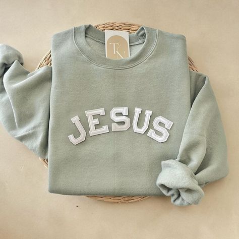 This Jesus crewneck sweatshirt is the perfect trendy minimalistic christian sweatshirt to declare your faith to the Lord! A great for your family, friends, or loved ones. - Sweatshirt is super soft and comfy! ♡  - Sweatshirt composition: 50% cotton, 50% polyester - All our sweatshirts run a unisex fit. They are naturally oversized, so we normally recommend your true size. But if you like a more baggy look, we recommend sizing up. - These letters are iron-on patched and is heat pressed, not embro Christian Embroidered Sweatshirt, Iron On Sweatshirt Ideas, Iron On Patches Ideas Clothes, Jesus Crewneck, Jesus Is King Shirt, Christian Sweatshirts, Jesus Clothes, Christian Shirts Designs, Jesus Sweatshirts