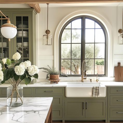 Olive green is one of the trending colors of the year! These cabinets play on trend while remaining a timeless contrast, and I love the warmth they add to this space. With a modern color, these rustic beams, farmhouse sink, and English cottage finishes help create a beautiful balance! AI Design: @oakhavendesignco . . . . . . . . . . #virtualdesign #virtualdesignservices #edesign #virtualhomedesign #moodboards #luxeathome #visionboards #prettylittleinteriors #interiorstyle #smmakelifebeauti... Arch Window Kitchen Sink, Arch Over Kitchen Sink, Arched Window Kitchen, Arched Kitchen Window, Olive Green Interior Design, Modern English Cottage Interiors, Kitchen Window Lighting, Light Over Sink, Rustic Beams