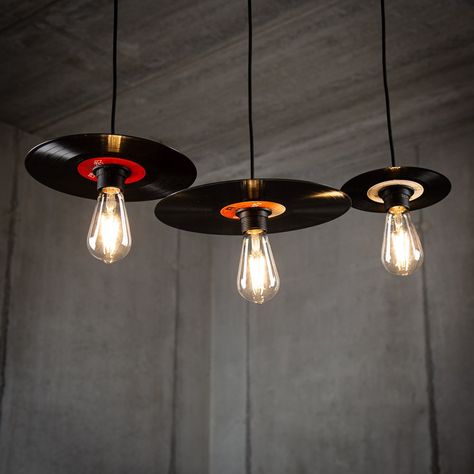 Elevate your space with a nostalgic touch and stylish ambiance by investing in our Retro Vinyl Record Lamp Pendant Set in a sleek black finish. Crafted from upcycled vinyl records, each lamp within the set is a unique piece of art, ensuring a distinct character for your lighting arrangement. 🎵💡 Available in versatile sets: - Set of 3 in 7-inch single size - Set of 3 in 10-inch EP size - Set of 3 in 12-inch LP size - Mix and match with a set featuring one of each size Handcrafted from authentic upcycled vinyl records, each lamp boasts individuality and may exhibit a variety of colors due to the upcycling process. The elegant black finish provides a modern and timeless aesthetic that complements various interior styles. Bulbs not included, offering you the flexibility to tailor the lightin Record Upcycle Diy, Vinyl Record Ceiling, Custom Lighting Design, Unique House Furniture, Music Bar Design, Retro Lamps Vintage, Record Lamp, Artistic Lamps, Living Room Lamps Ceiling