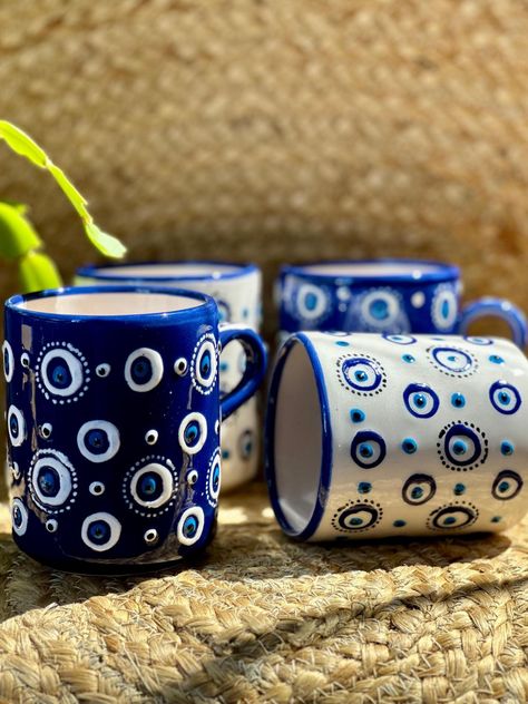 Transform Your Daily Routine with Our Handmade Evil Eye Ceramic Mug! Say goodbye to ordinary mugs and elevate your beverage experience with our exquisite Handmade Evil Eye Ceramic Mug. Perfect for the discerning coffee or tea lover, this mug combines beauty, craftsmanship, and a touch of ancient magic. Why This Mug? Striking Design: Featuring a mesmerizing Evil Eye motif, this mug is not just a drinkware item but a piece of art. The intricate design is believed to ward off negative energy and bring good fortune, making every sip a moment of positive energy. Superior Quality: Crafted from high-grade ceramic, our mug promises durability and a refined, elegant look. It's designed to be your trusty companion for your morning coffee, afternoon tea, or evening relaxation. Daily Protection: Embra Evil Eye Pottery, Evil Eye Mug, Evening Relaxation, Eye Ceramic, Ancient Magic, Name Paintings, Eye Motif, Handmade Evil Eye, Greek Pottery