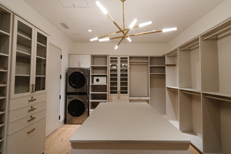 Antique burnished brass chandelier in Master custom closet in Los Altos Hills Home with island storage and washer and dryer. Custom closets by California Closets. #thedendesigngroup #mastercloset #customcloset #bayareainteriordesign #closetlighting #chandeleir #brasslighting #brasschandelier Walk In Closet Ideas With Laundry, Walkin Closet With Washer And Dryer, Master Closet Design With Laundry, Walk Through Closet To Bedroom Master Suite Layout, Washer And Dryer In Master Closet, Laundry In Master Closet, Master Closet With Washer And Dryer, Closet With Washer And Dryer, Master Closet With Island