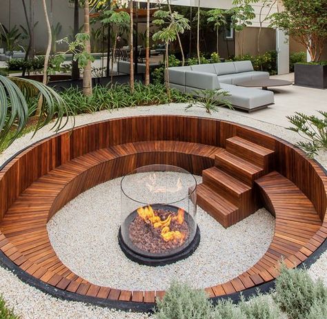 a contemporary sunken fire pit with a built in stained bench and steps plus a fire pit in the center clad with glass Sunken Patio, Sunken Fire Pits, Outdoor Fire Pit Designs, Fire Pit Landscaping, Fire Pit Seating, Backyard Fire, Backyard Garden Design, Fire Pit Backyard, Garden Seating