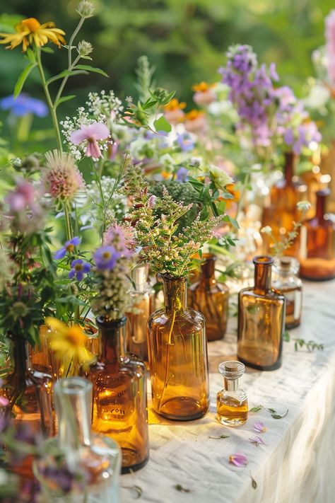 Elevate your wedding decor with a unique touch of the past. These vintage perfume bottles turned vases are filled with an array of herbs and wildflowers, perfect for a bohemian-themed celebration. 🌿🌼💐 A touch of nostalgia meets natural beauty for your special day. #WeddingInspiration #BohoWedding #CenterpieceIdeas #VintageDecor #FloralDesign #DIYWedding #EventStyling #WeddingFlowers Vintage Vases Wedding Centerpieces, Outdoor Wedding Floral Decorations, Vintage Table Decorations Wedding, Wild Flower Centerpieces Wedding Simple, Bohemian Chic Wedding Decor, Wedding Decor Wildflowers, Dried Flower Table Decor, Wildflower Vintage Wedding, Wildflower Wedding Theme Receptions