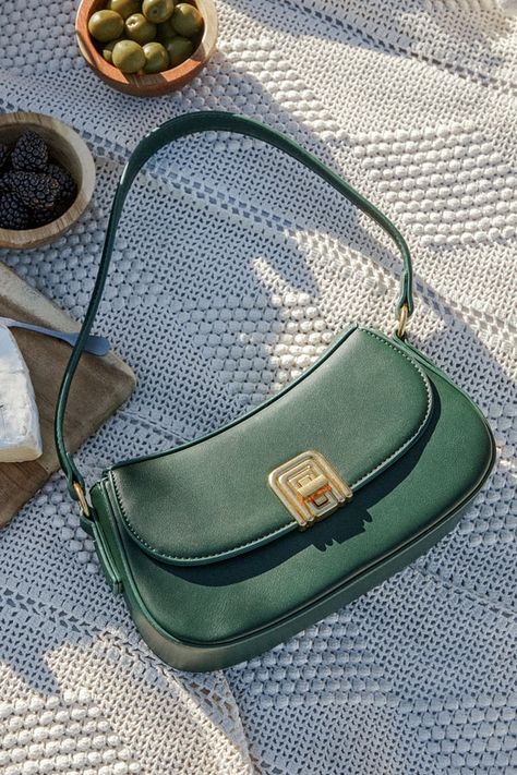 For an elegant accent to your next OOTD, look no further than the Picturesque Charm Green Vegan Leather Shoulder Bag! Smooth vegan leather shapes this chic bag that has a rectangular silhouette with a flat bottom design and a shoulder strap. Undo the gold turn clasp to reveal a roomy, lined interior with convenient side card slots and a zippered sidewall pocket. Shiny gold hardware throughout lends an elevated aesthetic! Lined. Bag measures 9. 75" wide, 5. 25" tall, and 2. 50" deep. Strap has a Baguette Purse, Cool Bags, Trendy Purses, My Style Bags, Bridal Handbags, Fall Bags, Green Handbag, Green Purse, Vegan Leather Bag