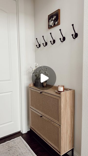 Nina Humes on Instagram: "small entryway 🤍✨

that is budget friendly and functional! This is the entry we have by our garage and my husband’s home office. We used to have a console here where I stored our shoes but when I stumbled on this cabinet that concealed everything I knew it would be absolutely perfect here! I LOVE it!

details here:
+ shoe storage cabinet: very affordable and under $80 🤯
+ black planter: Walmart
+ faux florals: these are from Hobby Lobby but found near identical ones on amazon
+ candle I love
+ little candle tray that is an older Target find
+ artwork from Amazon
+ washable runner
+ hooks: Amazon find (still deciding if I want to keep these here. I can still hang shorter sweaters and jackets but because this cabinet is taller than my last, I might remove them. We Small Entryways Shoe Storage, Entry Way Storage Ideas Small, Shoe Storage Entryway Small, Small Hallway Storage Ideas, Small Entryway Shoe Storage Ideas, Small Entryway Storage, Small Apartment Entryway, Little Candle, Apartment Entryway