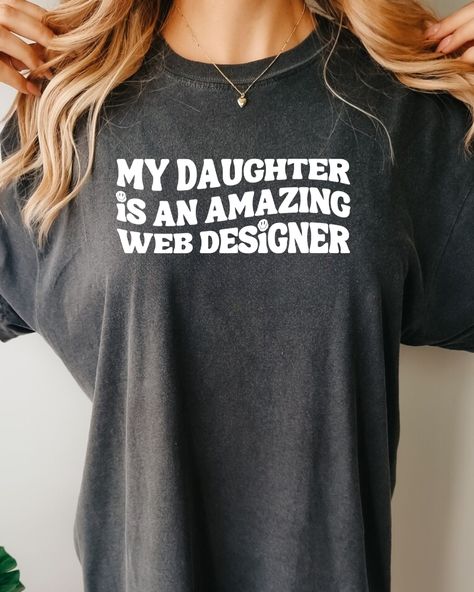 My Daughter is an Amazing Web Designer" t-shirt on a white background. The shirt features black text with the words "My Daughter is an Amazing Web Designer" in a bold font, centered on the chest. The shirt is made from 100% combed and ring-spun cotton and has a soft, comfortable feel. The image showcases the design and quality of the shirt, making it clear to potential customers what they will receive when they order. Walking Down The Street, Wife Humor, Queen Shirts, Web Designer, New Website, Dye T Shirt, My Daughter, Shirts For Girls, Perfect Fit