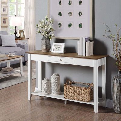 A console table is a versatile accent that works in many places in a home: from an entryway to a cluttered living room and beyond, the console table offers room to display decor pieces while also clearing up clutter. Take this one for example: Crafted from a blend of solid and manufactured wood, it strikes a clean-lined silhouette and boasts a neutral dark brown wood finish. An open bottom shelf provides a place to stack books and more, while a drawer up top keeps tabs on smaller treasured trink Entrance Table Decor Modern, White Console Table Decor, Cluttered Living Room, White Entry Table, White Entryway Table, Entrance Table Decor, Farmhouse Entry Table, Console Table With Shelf, Stack Books