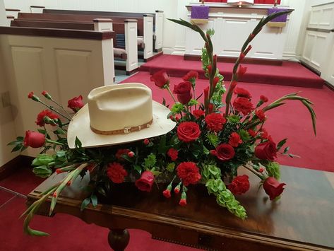 Memorial arrangement featuring his favorite cowboy hat Hat Memorial Display, Cowboy Hat Floral Arrangement, Cowboy Hat Flower Arrangement, Western Flower Arrangements, Red Flower Arrangements, Casket Spray, Casket Flowers, Service Ideas, Grave Flowers