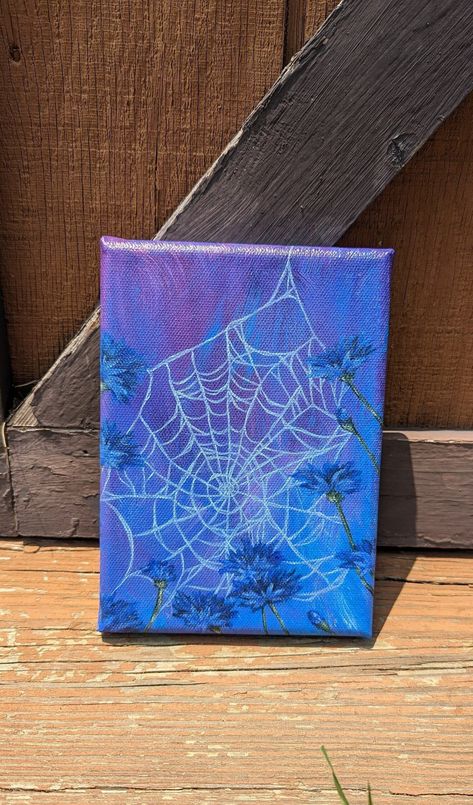 Size: 5 inches by 7 inches I've always been fascinated by the way spiders build their webs among flowers. They string the web from flower to flower creating the most intricate patterns. It's an interesting balance of the macabre and the cheerful. The result is something absolutely beautiful.    This acrylic painting features a spiderweb strung along blue cornflowers against a dreamy blurred and abstract background of purples, blues, and magentas. After studying spiderwebs in my backyard, I notic Blue Themed Painting Ideas, Whimsigoth Painting Ideas, Abstract Dark Painting, Decor For Blue Walls, Small Painted Canvas, Cute Spooky Paintings Easy, Purple Acrylic Painting Ideas, Dark Canvas Painting Ideas, Spider Painting Acrylic