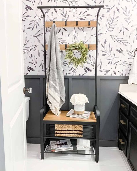 A cute farmhouse bathroom with neutral grey and white tones has a dark gray board and a batten wall with a gray and white branching wallpaper installed above. A charcoal-painted vanity with gold hardware and white counters coordinates with the neutral color scheme. Cute Farmhouse Bathroom, Vanity With Gold Hardware, Gray Board And Batten, Sherwin Williams Peppercorn, Board And Batten Bathroom, Batten Bathroom, Bathroom Wall Ideas, Modern Farmhouse Mudroom, Grey And White Bathroom