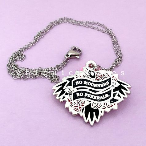 Silver pendant with chain with black and red crow and roses design. There are two black ribbons across the design that says "No Mourners, No Funerals." The Six Of Crows, The Grishaverse, No Mourners No Funerals, Bookshelf Art, Bookish Merch, Leigh Bardugo, Six Of Crows, Gifts For Readers, Enamel Jewelry