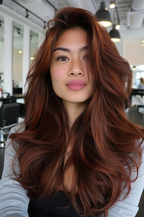 Woman with long, voluminous auburn hair in a salon setting. Dark Red Brown Hair Color Brunettes, Warm Tone Red Hair, Red Highlights For Dark Brown Hair, Balayage Copper Red, Auburn Dark Brown Hair, Brown And Auburn Balayage, Reddish Dark Brown Hair, Makeup For Auburn Hair, Dark Brown Caramel Highlights