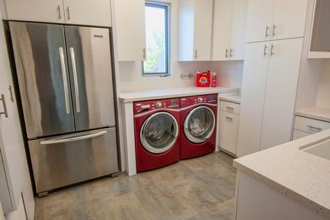 The red washer and dryer in this modern kitchen add a dose of color and functionality to the sleek white room. The counter space above the unit provides a perfect spot to fold clean laundry while enjoying the view out the window. Window Above Washer And Dryer, Traditional Mudroom, Red Washer And Dryer, Modern Kitchen Images, Modern White Kitchen, Modern Kitchen Ideas, Modern Kitchen Accessories, Kitchen Images, Small Laundry Rooms