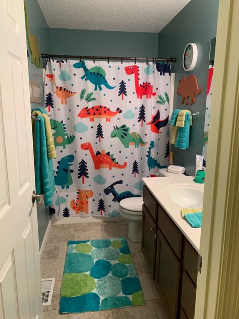 Wall dinosaurs are from Hobby Lobby. The wall clock, shower curtain, bath rug, and towels are from Amazon. The toothbrush holder is from Target. Dino Themed Bathroom, Dinosaur Theme Bathroom, Dino Bathroom Decor, Dino Themed Room, Kid Boy Bathroom, Toddler Bathroom Organization, Dino Bathroom Ideas, Dinosaur Themed Bathroom, Toddler Bathroom Ideas Boys