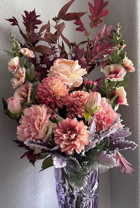 Very full arrangement filled with plum oak leaves, brown eucalyptus leaves, pink and cream hollyhocks, pink dried look hydrangeas, mauve and cream dahlias, cream rose with pink tips and dusty miller foliage. Purple Bohemian crystal vase not included in price but is available for purchase, Pink Fall Florals, Brown Eucalyptus, Pink Tips, Vase Cristal, Feuille Eucalyptus, Dusty Miller, Des Roses, Bohemian Crystal, Oak Leaves