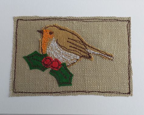 A sweet Christmas card featuring the traditional robin. He is made from fabric appliqued on to linen and stitched using freestyle machine embroidery in different coloured threads. Holly leaves and berries have been appliqued and stitched on too. Then the embroidery is sewn straight on to the card.  The card measures 21cm wide and 10cm high, comes with a white envelope and in a cellophane bag for protection. Inside is left blank for your own message.  Please note that this is a handmade item, the Embroidered Christmas Cards, Fabric Christmas Cards, Angel Christmas Cards, Sweet Christmas Card, Robin Christmas, Holly Leaves And Berries, Freehand Machine Embroidery, Christmas Quilt Patterns, A Robin