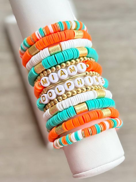 MIAMI DOLPHINS stackable bracelets are perfect for game days, or any day!  Some color shades may vary some.  EACH BRACELET SOLD SEPARATELY WITH OPTIONS TO PURCHASE AS A STACK. Right colors, but wrong team? Message seller to customize yours with your favorite team, mascot or slogan.  INSTRUCTION: 1. Select wrist size from the drop down menu. Each bracelet is custom made to size. (Please see photo for wrist sizing measurement.) 2. In the "Personalization" section, please notate any changes you would like to make. Examples of this would be band color or word changes.  **If no changes are made in the personalization section, bracelets will be made like photo.  📦📫FREE SHIPPING ON ALL DOMESTIC ORDERS OF $35 OR MORE! Care:  * Keep bracelets dry and away from soaps, lotions and chemicals. * Roll Nfl Bracelets, Heishi Jewelry, Keep Bracelet, Football Jewelry, Heishi Bracelets, Team Bracelets, Dolphin Bracelet, Homemade Bracelets, Dolphins Football