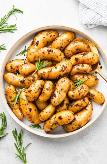 Roasted fingerling potatoes topped with herbs on a white plate ready to serve on white background Fingerling Potato Recipe, Finger Potatoes, Recipes Mashed Potatoes, Smothered Potatoes, Yummy Potatoes, Potatoes Fries, Grandbaby Cakes, Sweet Potato Dishes, Frugal Meal Planning