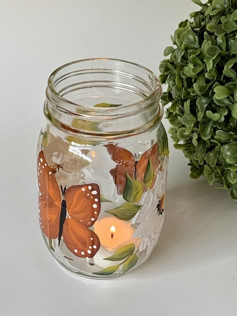 Glass mason jar with handpainted white daisies and butterflies, very happy design. Listing is for one jar with light. They are great as a decorative piece. Remove lights and use for candy or cookies. Wonderful for the bathroom as a toothbrush holder, great for spring and summer, very neutral. Great to use for mixed drinks, wine , sangria etc. Makes a great lemonade jar. Multiple usages, pretty and useful! They are great for gift giving, Cute Mason Jar Painting Ideas, Light Up Mason Jars, Jar Painting Ideas Cute, Jar Painting Ideas, Mason Jar Painting Ideas, Glass Jar Painting, Mason Jar Painting, Painting Mason Jars, Lemonade Jar