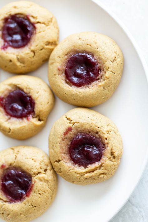 Peanut Butter & Jelly Fans, gather - you won’t be able to resist these nutty and jammy little gems. These yummy  Vegan PB & J Thumbprint Cookies turn a favourite childhood sandwich into a tasty lunchbox treat. 7 ingredients, no added oil! Perfectly paired with a glass of milk, these easy vegan cookies are for the kid in every one of us. #cookierecipes #easyrecipes #pbandj #peanutbutterandjelly #vegandesserts Jelly Thumbprint Cookies, Vegan Lemon Curd, Easy Vegan Cookies, Healthy Peanut Butter Cookies, Tahini Cookies, Jelly Cookies, Vegan Richa, Thumbprint Cookies Recipe, Peanut Butter Oatmeal Cookies