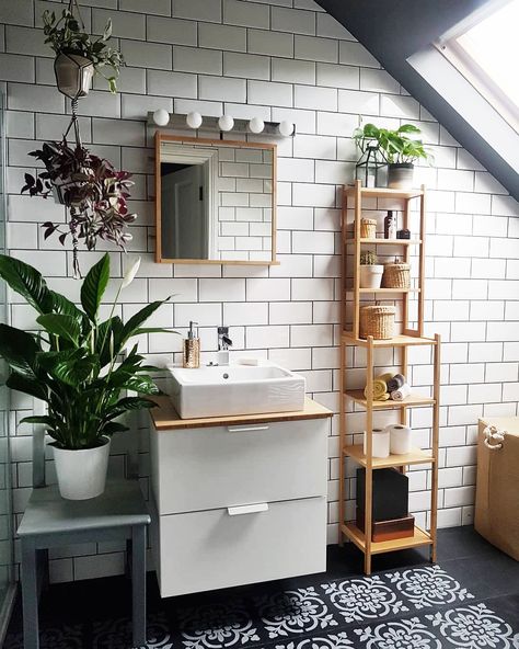 White subway tile and black floors pair perfectly in this bathroom. Finished with natural wood accents and lots of green plants, this bathroom design feels like a tranquil space. #bathroomdesign #bathroomideas #blackandwhitebathroom #bathroomdecor Drømme Bad, Sink Mirror, Monochrome Bathroom, Bad Inspiration, Vinyl Decor, Trendy Bathroom, Green Bathroom, Painted Floors, Cheap Decor