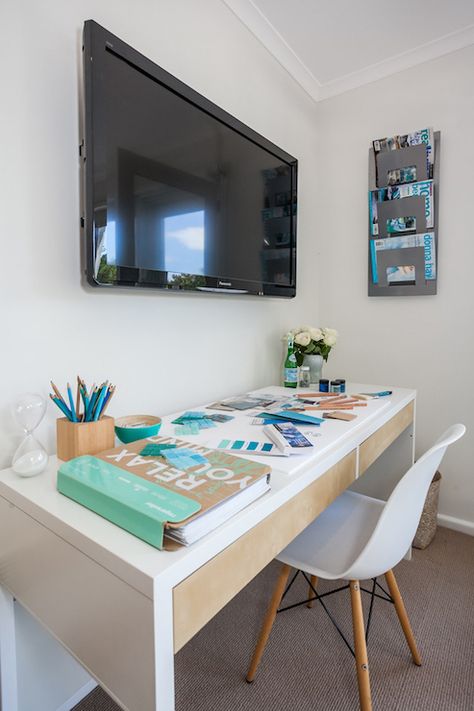 Coastal style office features a flatscreen TV over a white desk with two drawers paired with an Eames Molded Plastic Chair across from a wall mounted magazine holder. Chic Workspace, Coastal Style Kitchen, House Of Turquoise, Bedroom Desk, Trendy Bedroom, Bedroom Layouts, Office Spaces, Casual Office, Office Inspiration