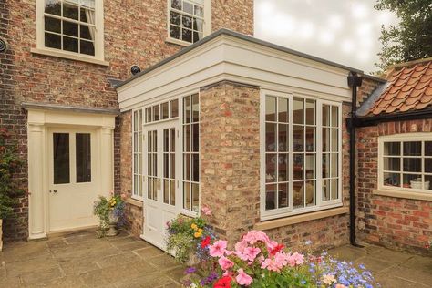 Flat roof extension adjoining the main house, which is constructed from brick columns, timber doors and windows all in white. A nicely moulded timber fascia around the perimeter. Brick Parapet Design, Flat Roof Kitchen Extension, Flat Roof Fascia, Flat Roof Extension Ideas, Extension With Lantern Roof, Brick Orangery Extension, Brick Extension With Bifold Doors, Orangery With Bifold Doors, Orangery Kitchen