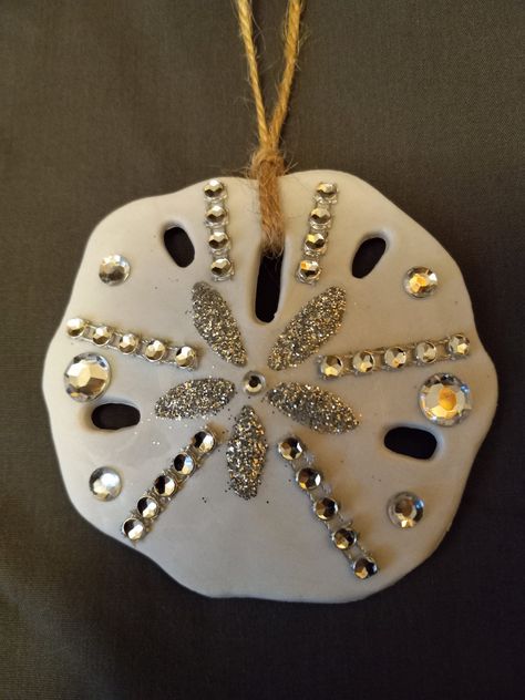 A 3 inch sand dollar. Hand painted,glittered by hand. Embellished with rhinestones. With a twine hanger. Things To Make With Sand Dollars, Sand Dollar Christmas Ornaments Diy, Sand Dollar Christmas Ornaments, Sand Dollar Decor, Beach Theme Candles, Painted Sand Dollars, Sand Dollar Craft, Sand Dollar Art, Sand Dollar Ornament