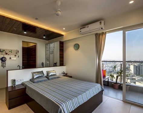 Modern Bedroom with Wooden 🛏 Bed, Side Table, Wooden Headboard & 📚 Study Table behind it with Wooden 🪑 Chairs & White Board on Wall, Wooden 👕 Wardrobe, Wall 🕐 Clock, French Windows & Wooden False Ceiling with Cove & Recessed ✨ Lighting - GharPedia Bedroom With Wooden Bed, Board On Wall, Wooden False Ceiling, Wooden Bed Side Table, Side Table Wooden, Wardrobe Wall, Bed Side Table, Wooden Chairs, French Windows