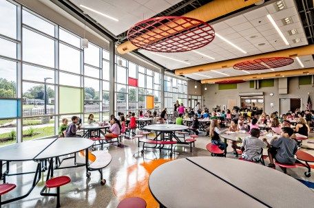 Bright, fun, and colorful. Cafetorium transforms from a lunchroom into a performance space, featuring acoustical baffles, a sound system, and performance lighting. Exposed building systems encourage systems thinking. | Cafeteria + Auditorium | Steger Intermediate Center | DLA Architects School Architecture Design, School Interiors, Elementary School Architecture, School Lunchroom, Cafeteria Design, School Cafe, School Designs, American High School, Systems Thinking