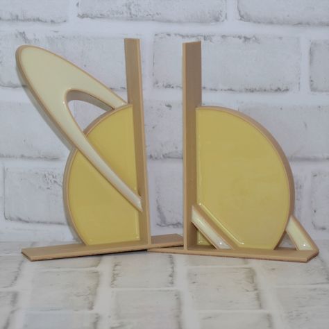 This is a set of two handmade, lightweight Saturn bookends. I design them using engineering software and then 3D printed them in a wood infused PLA. I then fill the prints with colorful resins. The bookends are then finished off with a cork bottom. I hope you enjoy looking at what I make! My partner owns a 3D printing business. We were intrigued by epoxy resin art, as it produces such brilliant colors and products. We had the idea to merge the 3D printing skill with resin art and turned it into Astronomy Decor, Science Decor, 3d Printing Business, Science Gifts, Book Ends, Epoxy Resin Art, Impression 3d, Printing Business, My New Room