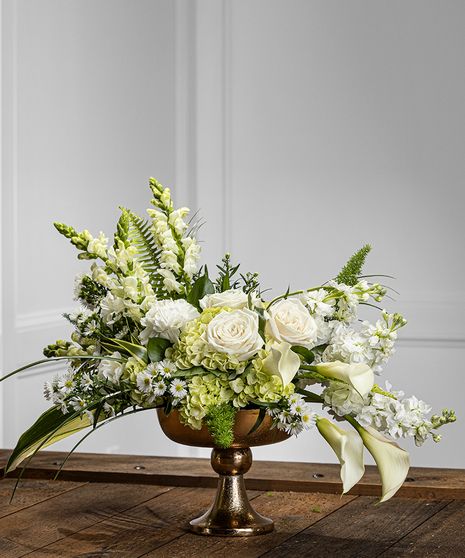 Our white contemporary pedestal design features stunning garden hydrangea, white calla, stock, snapdragons, mountain roses, seasonal fillers and foliage, and presented in a gorgeous gold pedestal for a unique and dramatic display. Trophy Flower Arrangement, All White Arrangements, Floating Hydrangea Centerpiece, White And Green Arrangements, White Flower Arrangements Centerpieces, Large Flower Arrangements For Home, All White Floral Arrangements, White Floral Centerpieces Wedding, Green And White Flower Arrangements