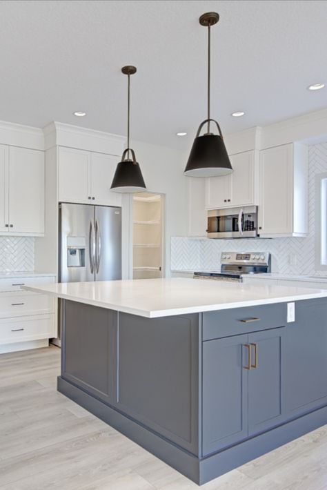 This beautiful kitchen features white quartz countertops, white cabinets with grey island, stunning black feature pendants, herringbone tile backsplash and gold faucet White Kitchen Cabinets Black Countertops Grey Floor, Kitchen White Cabinets Grey Floor, White Kitchen And Grey Island, White Cabinet Grey Island, White Dark Grey Kitchen, Kitchen Grey And White Cabinets, Decorative Backsplash Kitchen, Black White Grey Gold Kitchen, Light Grey Tiles Kitchen